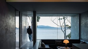 A modern interior with a large window offering a view of a body of water and distant mountains. - Vipp Tunnel - Tasmania (Apollo Bay)