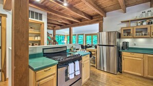 A spacious kitchen with wooden beams, a stainless steel refrigerator, and a green countertop. - the wooder house: charming haven in the woods, family-friendly & dog-friendly (Nellysford)