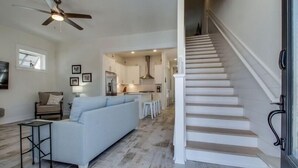 Un interior moderno con una escalera, una sala de estar con un sofá y una zona de cocina.