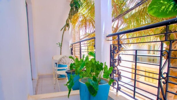 A balcony with potted plants, a chair, and a metal railing. - dakar International House (Dakar)