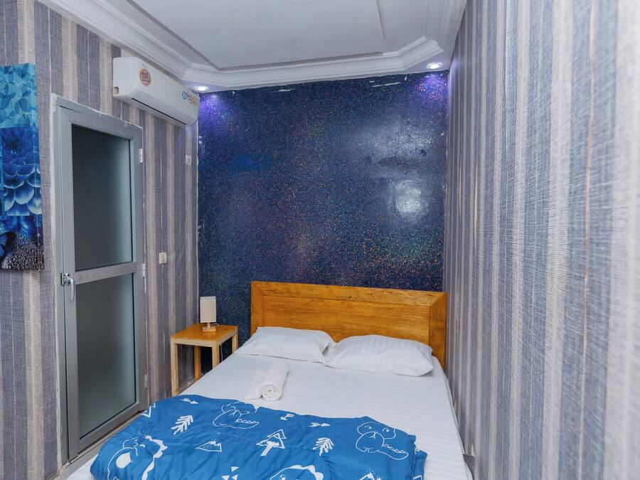 A hotel room with a bed, a nightstand, a wall with a starry pattern, and a door.