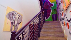 A staircase with a metal railing, a colorful mural on the wall, and a painting of an elephant. - dakar International House (Dakar)