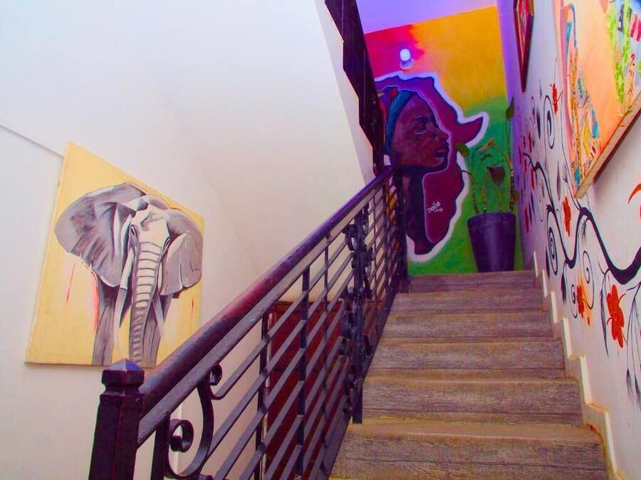 Una escalera con barandilla de metal, un mural colorido en la pared y una pintura de un elefante.