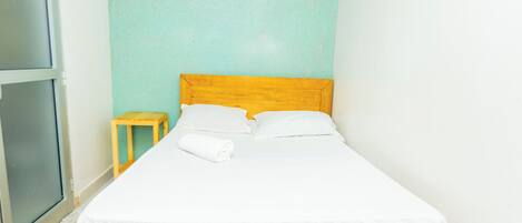 Una cama individual con cabecera de madera, ropa de cama blanca y una mesita de noche de madera.