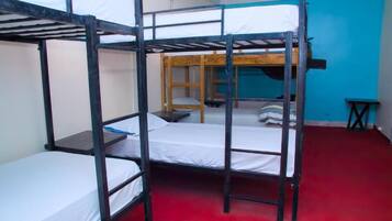 A bunk bed room with a red carpet, a small table, and a chair.