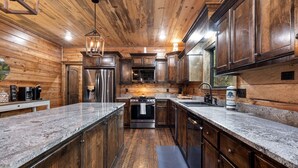A modern kitchen with wooden cabinetry, granite countertops, stainless steel appliances, and a central island.