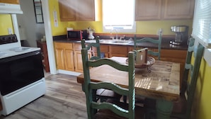 A kitchen with wooden cabinets, a microwave, a sink, and a dining table with chairs.