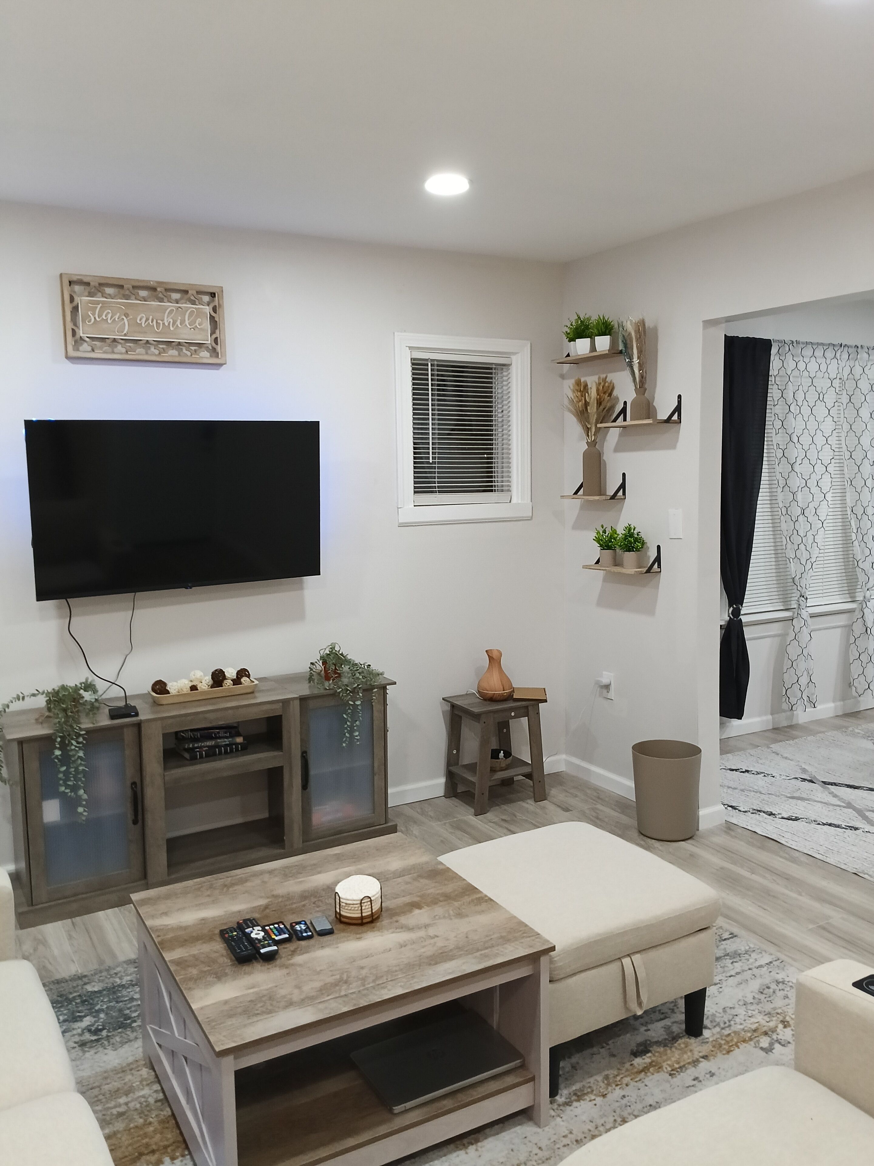 Una sala de estar moderna con un televisor de pantalla plana, una mesa de centro de madera y un sofá color beige.