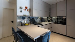 Une cuisine moderne dotée d’un îlot central, d’appareils électroménagers intégrés et d’œuvres d’art décoratives murales.