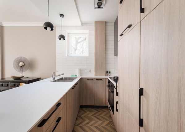 A modern kitchen with a white countertop, wooden cabinets, and a herringbone-patterned floor.