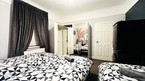 A hotel room with two beds, a large window with curtains, a wardrobe, and a door leading to another room. - Ground Floor Entire Holiday Apartment - Self Check in/out - Perfect for 6 Guests (Crossgates)