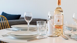 Une table à manger dressée avec des assiettes, des verres, des couverts et une bouteille de vin.