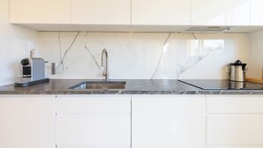 Une cuisine moderne avec des armoires blanches, un pare-feu en marbre et des appareils électroménagers en acier inoxydable.