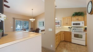 A modern kitchen with wooden cabinets, a microwave, an oven, and a dining area with a table and chairs.