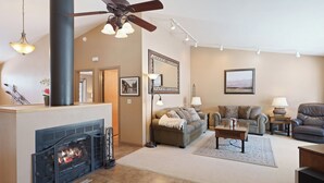 A living room with a fireplace, sofa, and a ceiling fan.