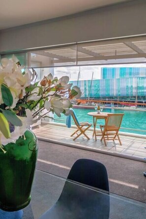 Enjoy a serene view of the marina from this stylish room, featuring a glass table and comfortable seating for two.