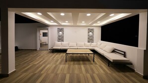 A modern living room with a sectional sofa, a coffee table, recessed ceiling lighting, and a wooden floor. - 3-bedroom apartment in marvelous Puerto Plata with AC, WiFi (Puerto Plata)