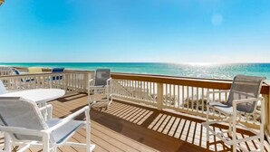 A wooden deck with white chairs and a table, overlooking a beach with clear turquoise water. - Free Beach Service~ Beachfront Townhome ~ Sleeps 8-GreenReef #4 (Destin)