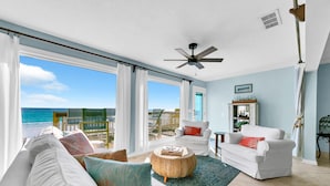 A spacious living room with a view of the ocean, white furniture, and a ceiling fan. - Free Beach Service~ Beachfront Townhome ~ Sleeps 8-GreenReef #4 (Destin)