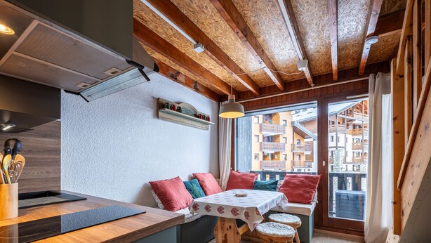 A cozy kitchen with wooden beams, a built-in stove, and a window overlooking a residential area. - Cosy mezzanine studio for 4 ppl (Morillon)