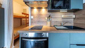 A compact kitchenette with a microwave, oven, and sink. - Cosy mezzanine studio for 4 ppl (Morillon)