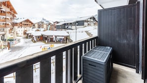 A balcony with a view of a snow-covered ski resort, including buildings and a mountain in the background. - Cosy mezzanine studio for 4 ppl (Morillon)