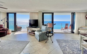 Relax in this stylish living area with a large TV, comfortable seating, and a balcony offering ocean views.