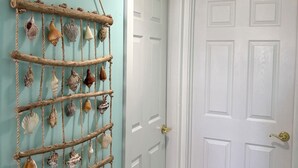 A hallway with a white door, a wall-mounted shell rack, and a ceiling light fixture.