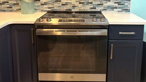 A kitchen with dark cabinets, a stainless steel microwave, a gas stove, and an oven.