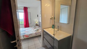 Une salle de bain avec un grand miroir, un lavabo et un espace douche.
