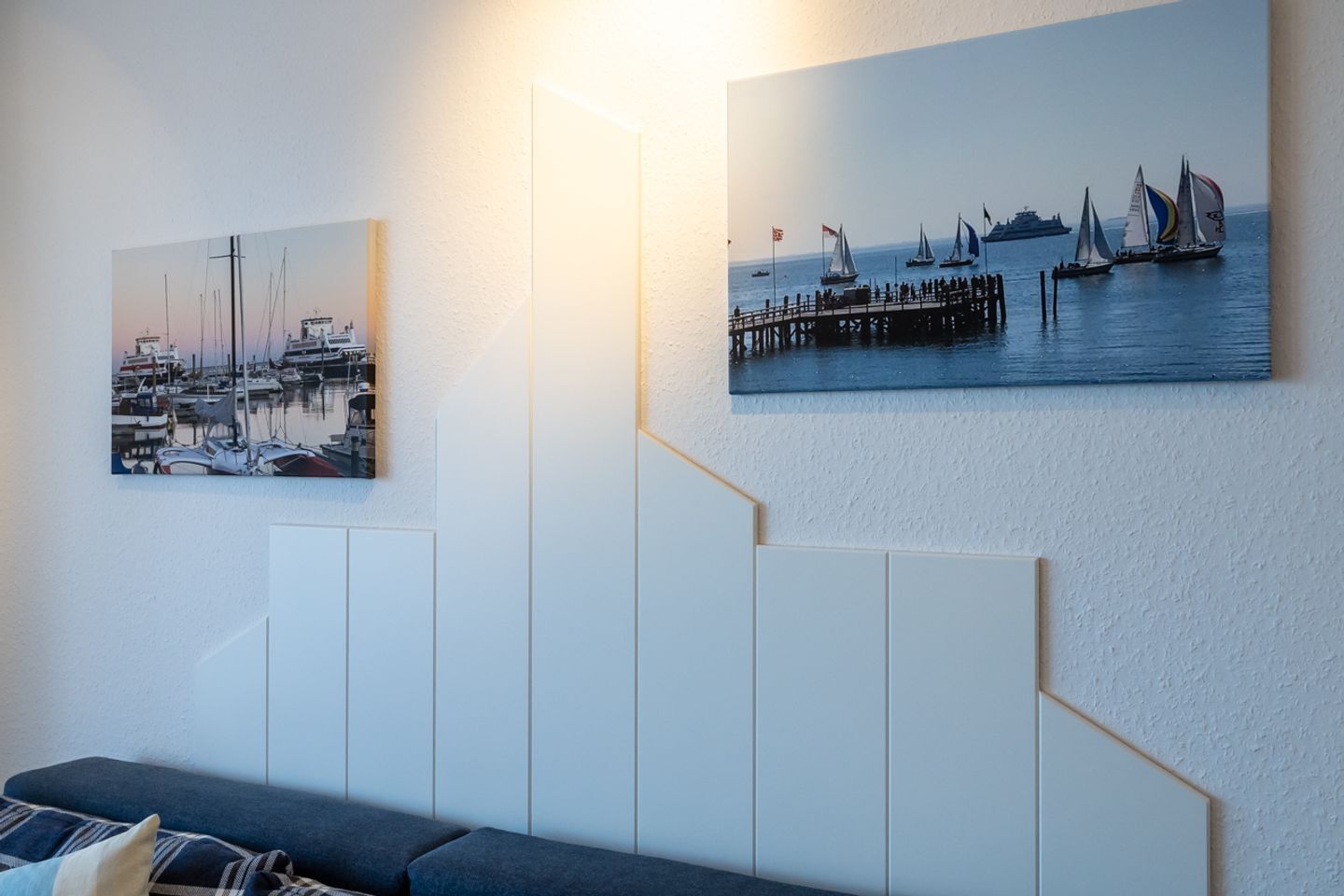 En vägg med två tavlor med marint tema och en modern, vit paneldesign.