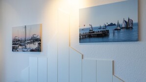 A wall with two maritime-themed paintings and a modern white panel design. - In 2nd row to the beach - Gmelinstraße 8 (Wyk auf Föhr)