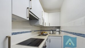 A compact kitchen with white cabinets, a black stove, and blue-tiled backsplash. - In 2nd row to the beach - Gmelinstraße 8 (Wyk auf Föhr)