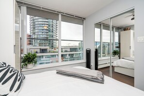 Une chambre moderne avec une grande fenêtre, un lit, un radiateur et une plante en pot.