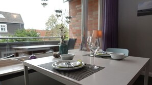 Una mesa de comedor dispuesta con platos, cubiertos y una copa de vino, con un florero de flores y una vela sobre la mesa.