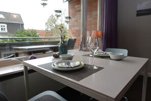 A dining table set with plates, cutlery, and a wine glass, with a vase of flowers and a candle on the table.