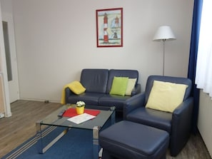 Un salon comprenant un canapé, une table basse et une lampe.