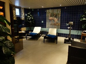 Une pièce avec deux fauteuils confortables, un grand tableau représentant des flamants roses et un mur recouvert de carreaux.