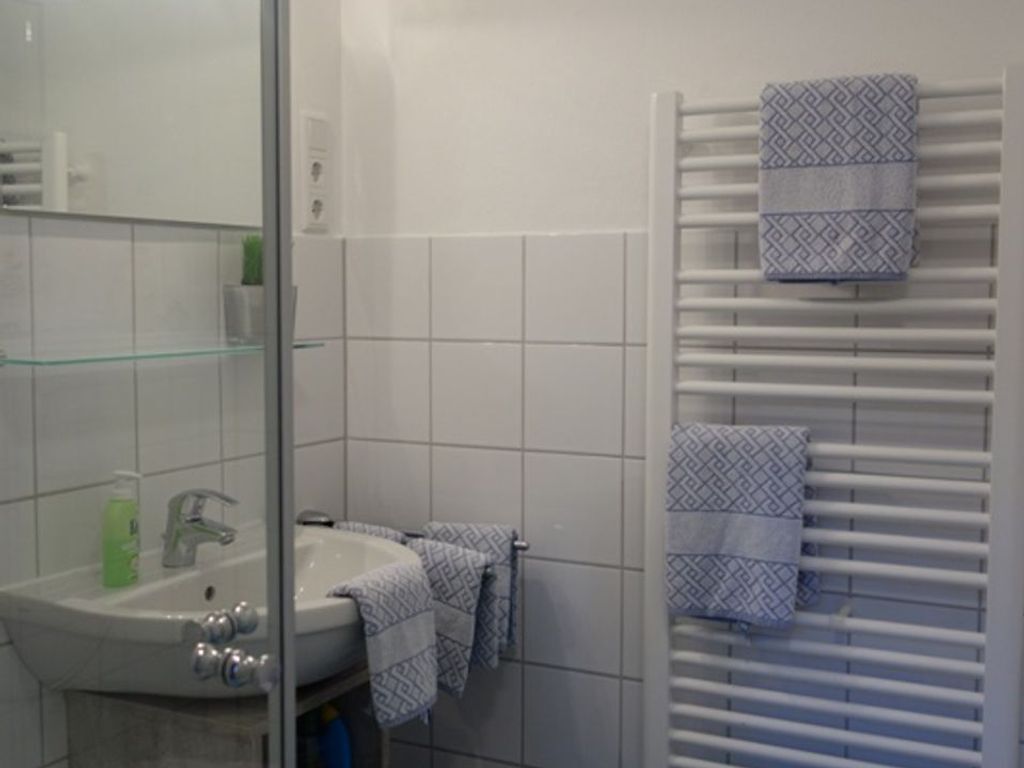 Une salle de bain avec une douche à parois de verre, un lavabo blanc avec un robinet et un porte-serviettes avec des serviettes à motifs.