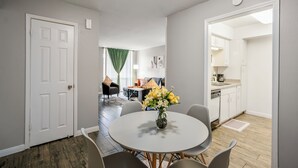 A modern kitchen with white cabinets, a dishwasher, and a countertop with a coffee maker.