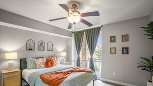 A bedroom with a bed, nightstands, a ceiling fan, and a window with curtains.