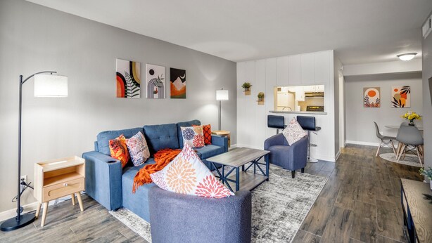 A modern living room with a blue sofa, a coffee table, and a dining area with a small table and chairs.