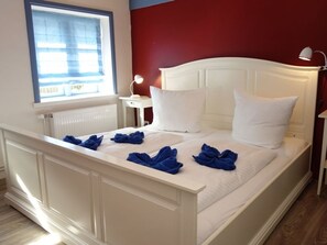 Un lit avec une tête de lit et des oreillers blancs, des serviettes bleues et une table de chevet avec une lampe.