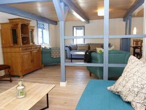 A room with a wooden cabinet, a sofa, a table, and a hanging light fixture.