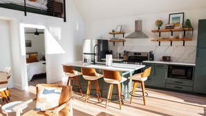 Un appartement moderne de style « loft », comprenant une cuisine, un coin repas et une chambre.
