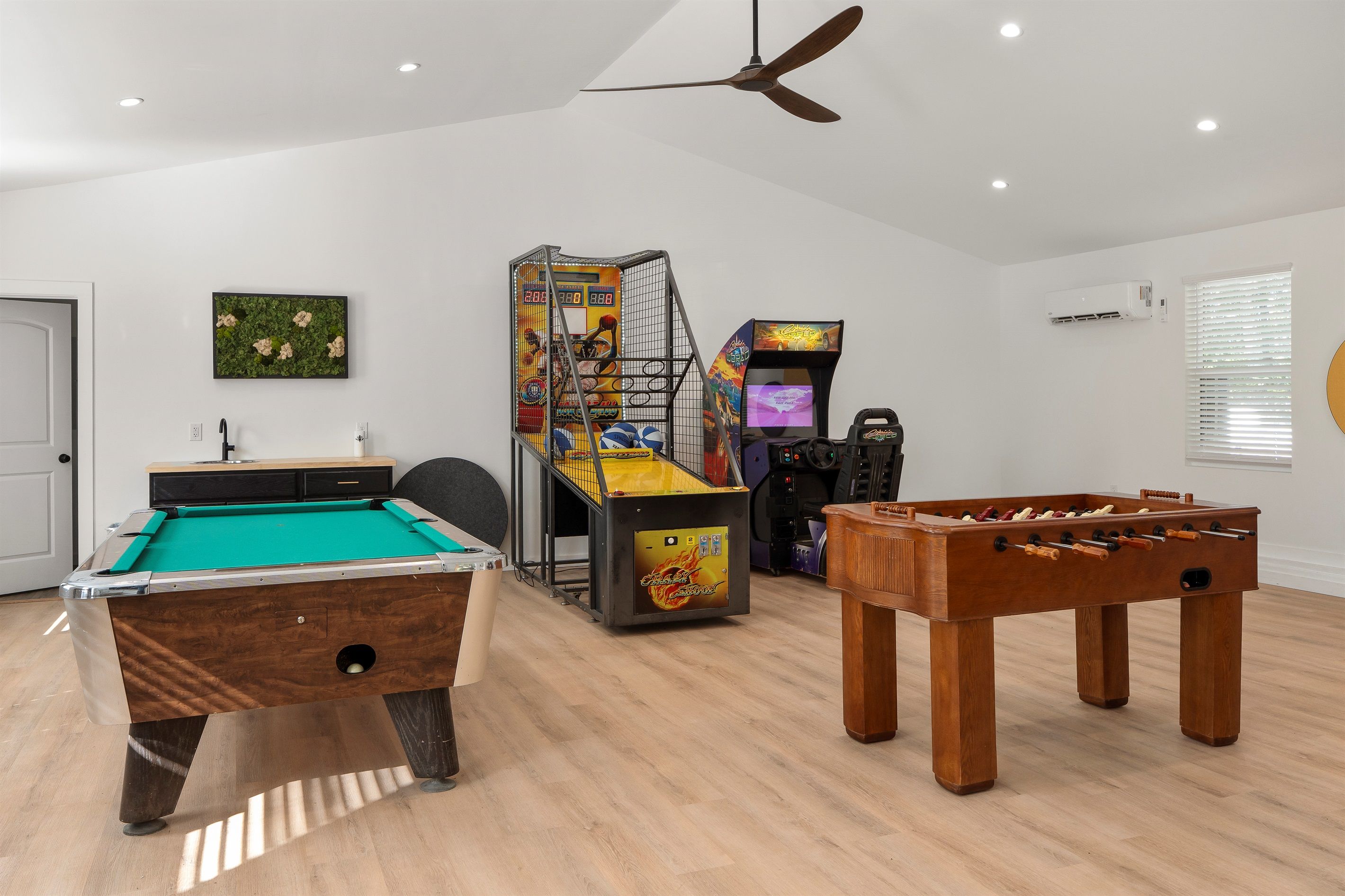 A room with a pool table, foosball table, and arcade games.