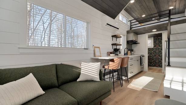 A modern kitchen with a dining area, a sofa, and a staircase.