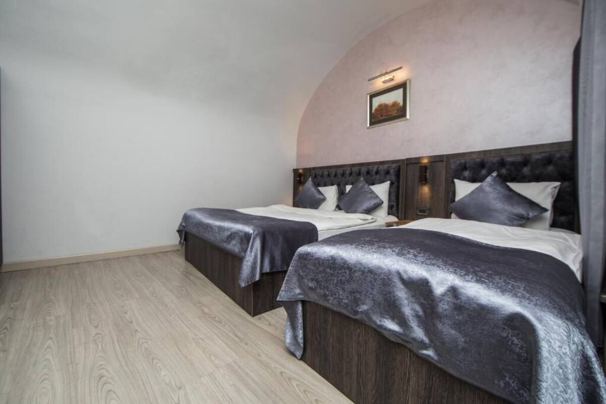 A bedroom with two beds, a wooden floor, and a picture on the wall.