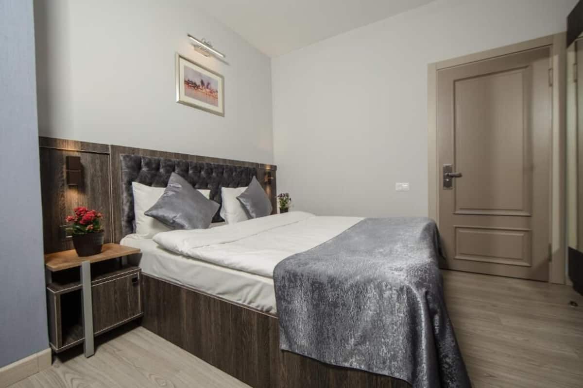 A bedroom with a bed, nightstands, a dresser, and a door.