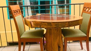 Una mesa redonda de madera con dos sillas, cada una con asiento y respaldo acolchados, sobre un suelo de baldosas.
